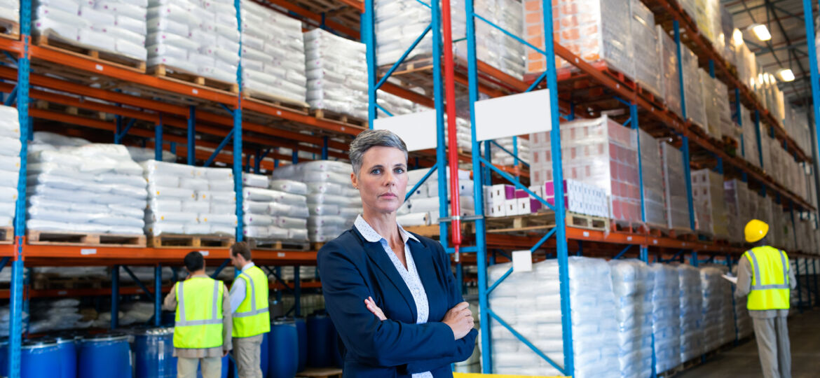 Female manager standing with arms crossed and looking at camera in warehouse