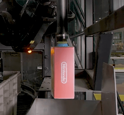 Robotic arm and SpectrumGripper picks an electronic SKU for placement in a sortation shuttle