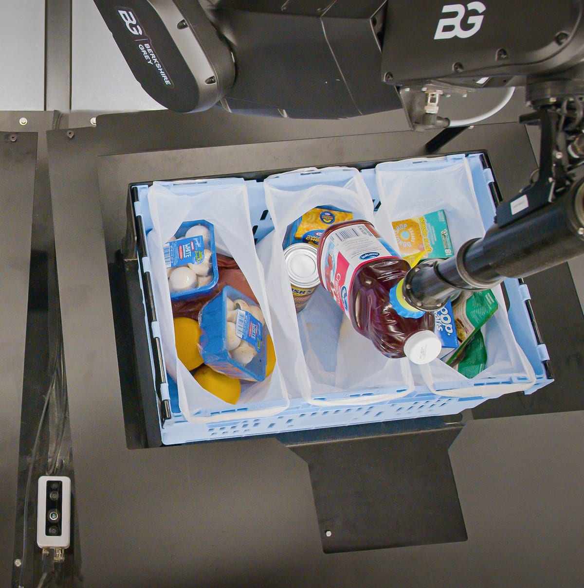 Robotic arm and SpectrumGripper picks a grocery SKU for placement in a bag