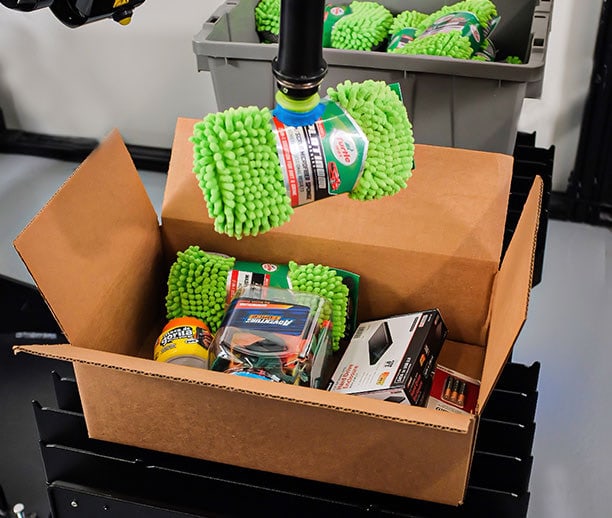 Robotic automation systems work together to pick an auto store item and place in a box for order fulfillment.