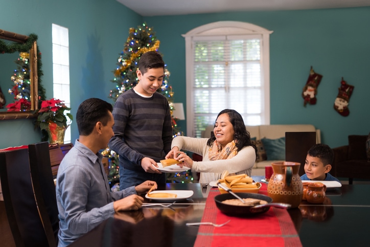Mexican family on Christmas eating together sitting on their Mexican home.
