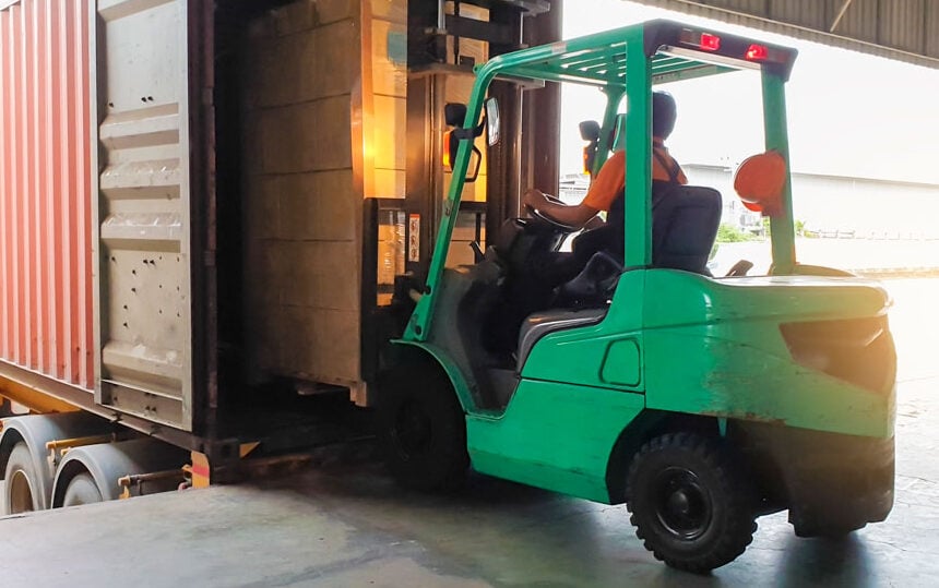 A forklift operator unloads a large pallet of goods.