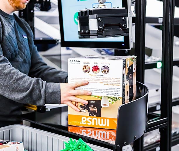 Berkshire Grey Robotic Shuttle Put Wall operator is barcoding a SKU to be sorted to fulfill a customer order.
