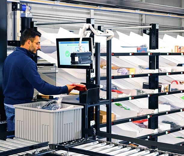 An operator bar-codes SKUs into a Robotic Shuttle Put Wall (BG RSPWi) solution to sort eCommerce orders for fulfillment.