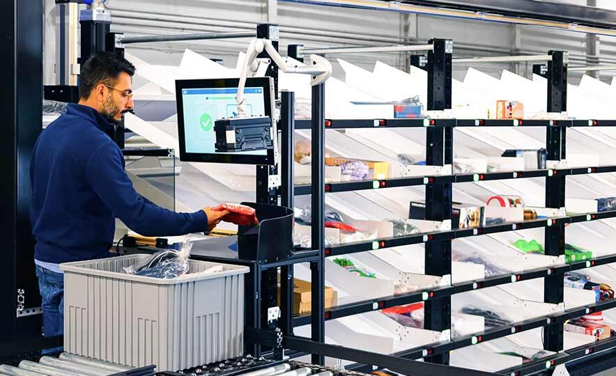 Berkshire Grey Robotic Shuttle Put Wall operator is barcoding a SKU to be sorted for an eCommerce order