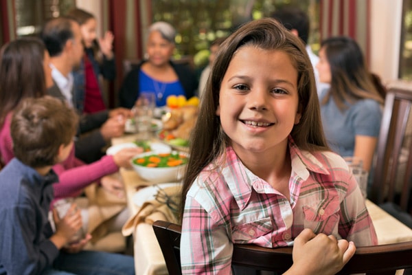 A multi-cultural multi-generational family gathers for a holiday meal to celebrate.