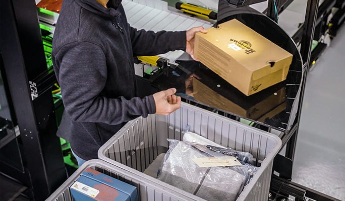 The operator scans the SKU barcode for input into the robotic shuttle put wall